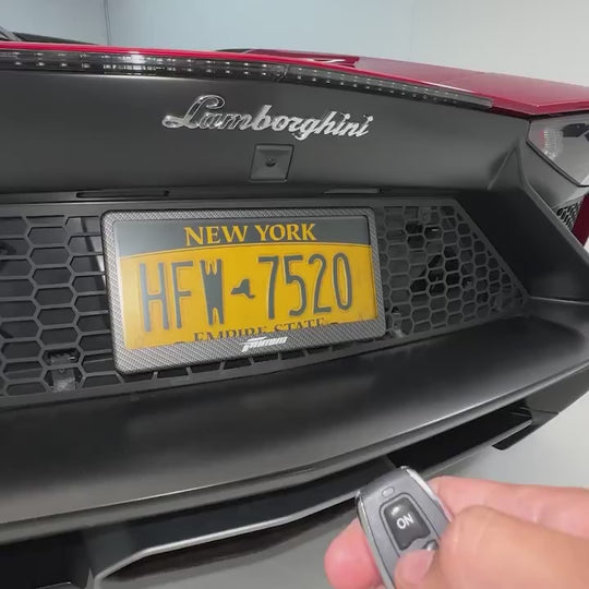 Hand pressing the remote as the Fantom blackout license plate switches to black on a Lamborghini