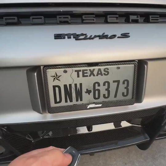 Fantom blackout license plate with carbon fiber frame switching from black to clear on a Porsche 911 Turbo S